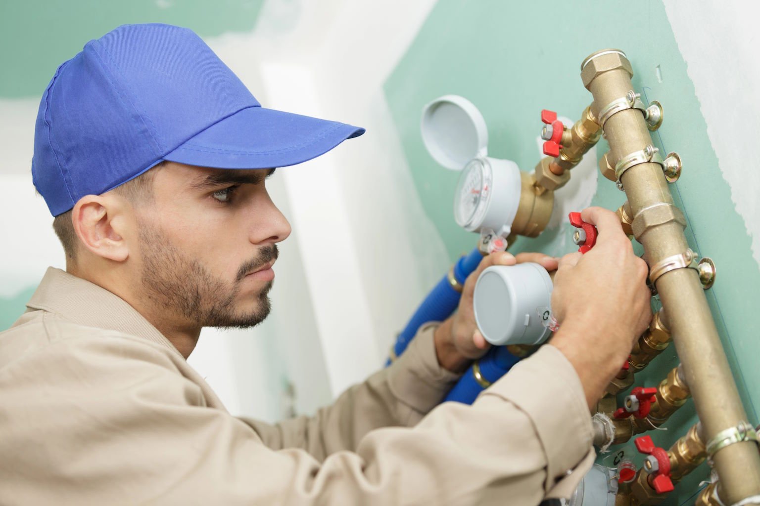 Plumber working on a brass pipe manifold with valves (demo image)